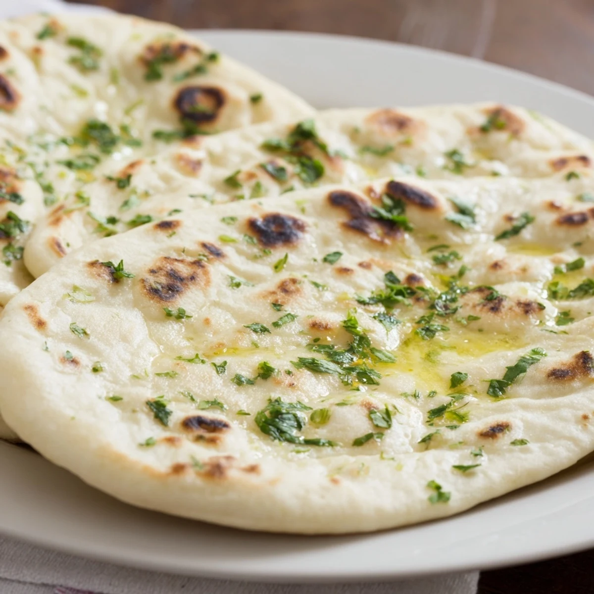 Freshly baked Homemade Garlic Naan Bread, golden brown and brushed with fragrant garlic butter, ready to eat.