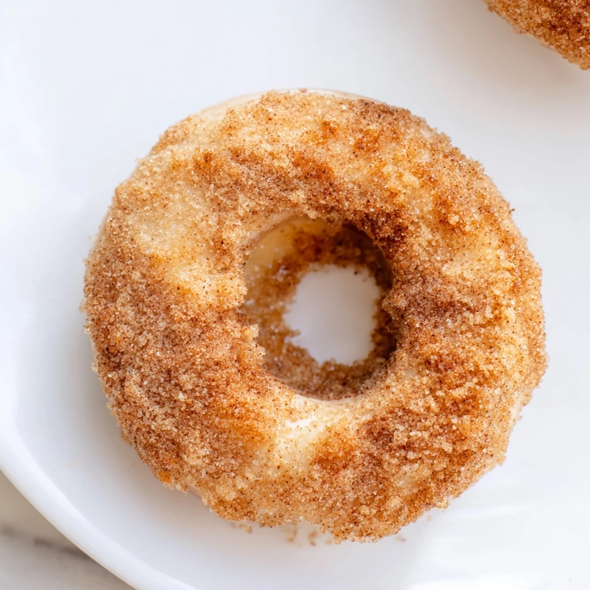 A close-up of freshly made 1-Minute Air Fryer Donuts, still glistening after being tossed in cinnamon sugar.