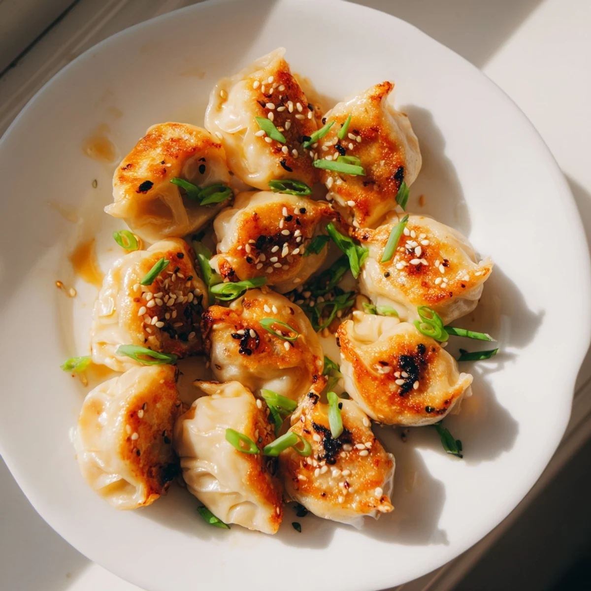 Golden-brown air fryer frozen dumplings, garnished with sesame seeds and green onions, a perfect snack.