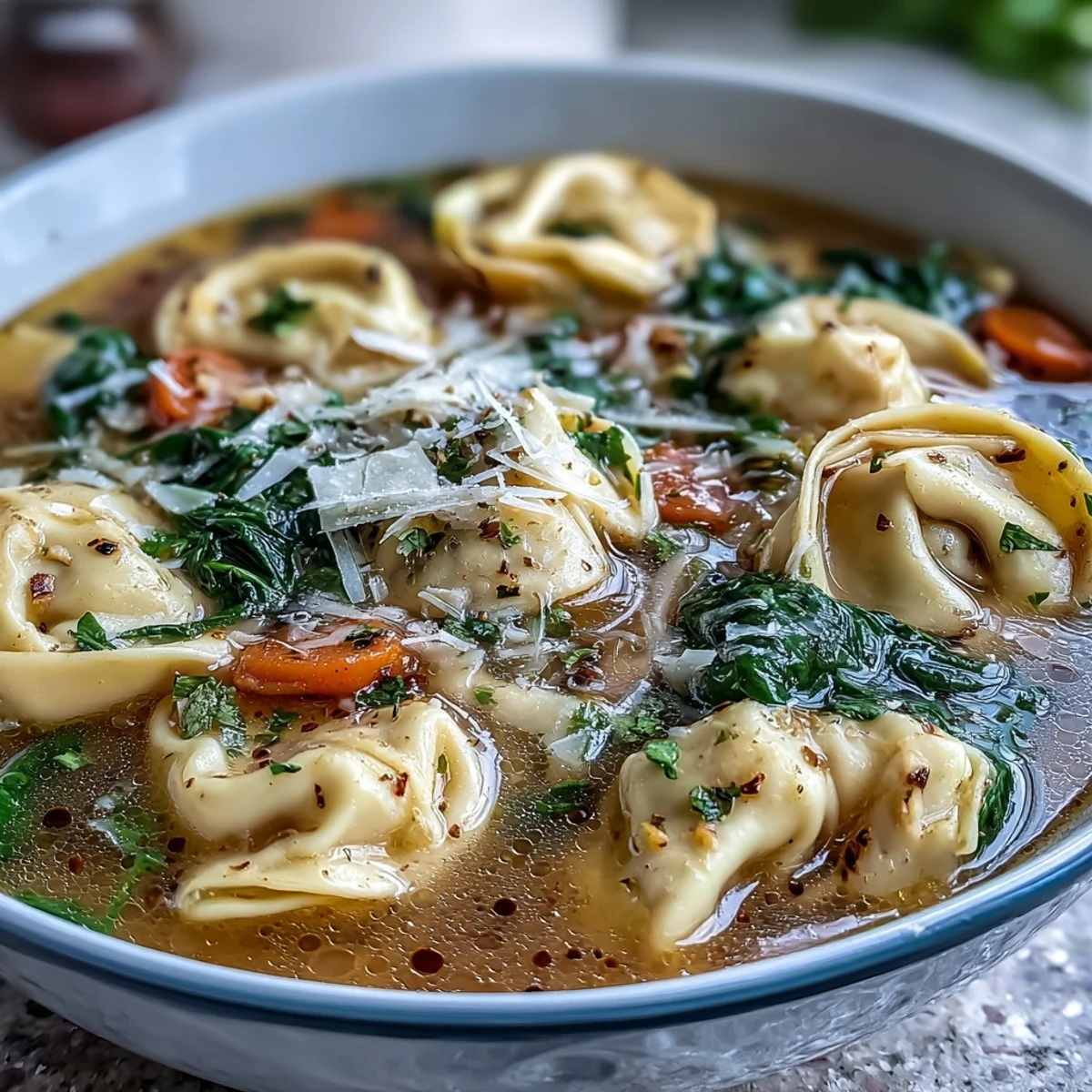 Spoonful of cheesy tortellini in a creamy broth, topped with fresh parsley and grated Parmesan for a cozy Italian-American meal.