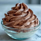 Spoonful of airy chocolate Protein Fluff being scooped from a bowl, showcasing its fluffy, mousse-like texture.