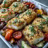 Parmesan Crusted Sheet Pan Fish is garnished with fresh parsley and lemon wedges, ready to serve with colorful roasted vegetables.