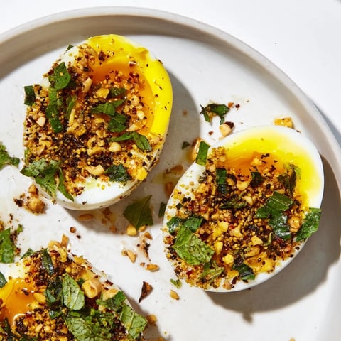 Golden-yolked Dukkah-Spiced Eggs, vibrant with fresh herbs and a delicious, crunchy dukkah spice topping.