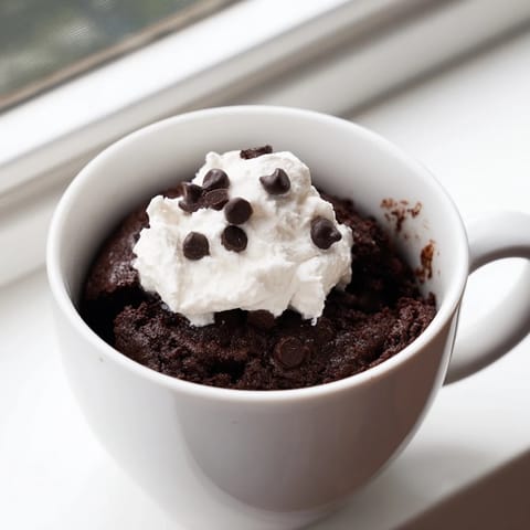 A close-up of a warm, chocolate mug cake ready in minutes, smelling wonderfully chocolatey.