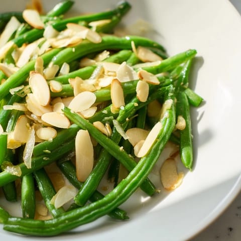 Bright green Sautéed green beans, glistening with olive oil, are topped with toasted almonds.