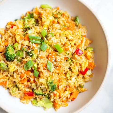 A steaming bowl of vegetable fried rice, showing off perfectly fried rice and fresh cilantro.