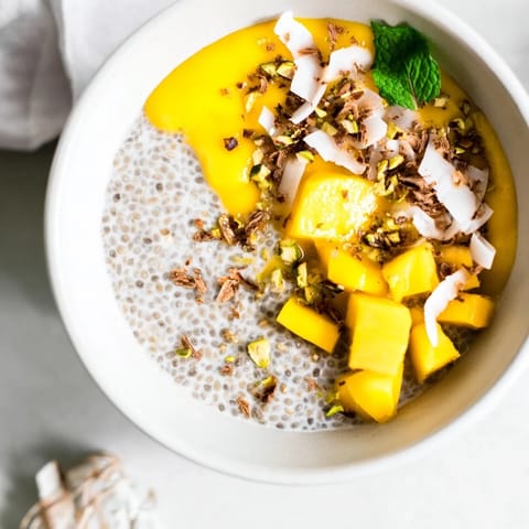A beautiful close-up of Mango Coconut Chia Pudding, topped with toasted coconut and fresh mango pieces.