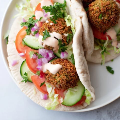 A delicious falafel pita pocket, freshly assembled with creamy tahini and crunchy, flavorful falafel.