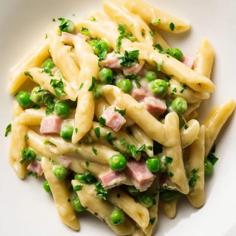 Bright green spring peas and diced ham mingle in a creamy sauce tossed with tender penne pasta, ready to serve warm.