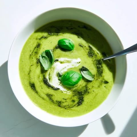 Courgette, Pea and Pesto Soup steaming in a rustic bowl, featuring a bright green puree and a drizzle of pesto.