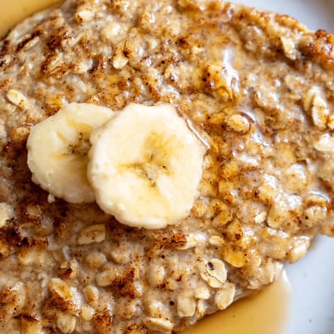 Moist and fluffy Banana Oat Pancakes served warm with fresh berries, a dollop of yogurt, and a sprinkle of cinnamon.