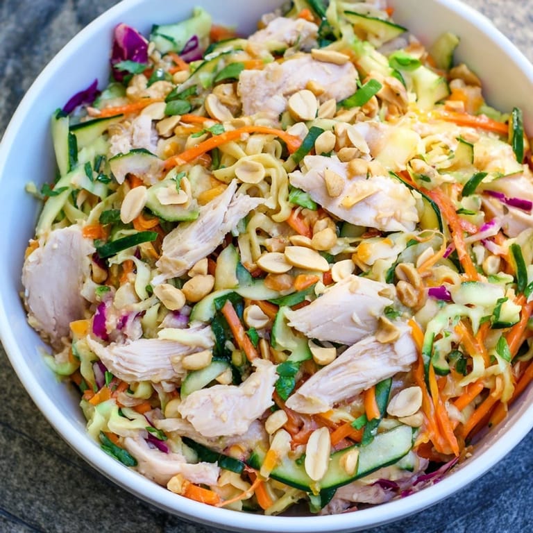 Enjoy a bowl of refreshing Thai-Inspired Peanut Chicken Pasta, complete with peanuts and colorful bell peppers.