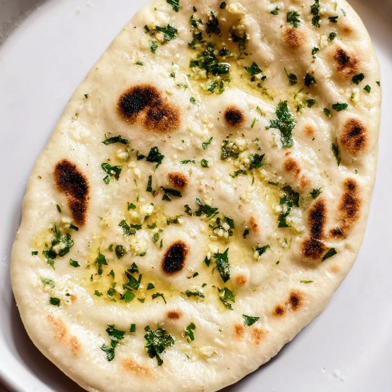 Steaming hot, fluffy Homemade Garlic Naan Bread shows the visible bubbles, perfect to tear and dip.