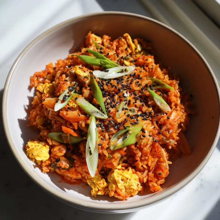 Steaming Spicy Kimchi Fried Rice in a hot skillet, featuring caramelized kimchi, diced onions, and gochujang mixed into day-old rice.