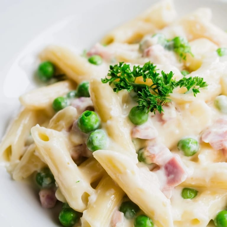 Tossing cooked penne with savory leftover ham, fresh spring peas, and a rich Parmesan cream sauce in a skillet.